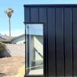 A dark metal-clad guest home with a tall glazed corner