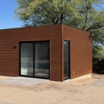 A wood-clad guest home with a sliding glass door, on a desert lot